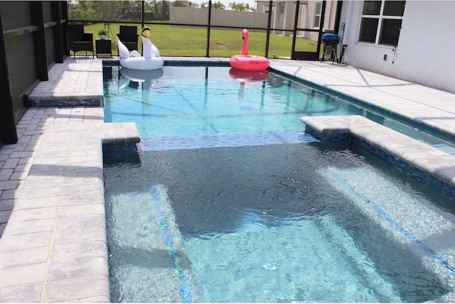 view of pool with area for grilling, a pool with connected hot tub, a lanai, and a patio area