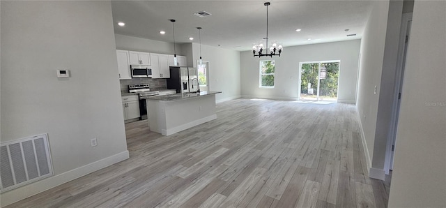 kitchen featuring light hardwood / wood-style flooring, decorative light fixtures, stainless steel appliances, white cabinetry, and a center island with sink