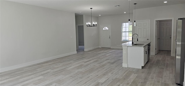 kitchen with a kitchen island with sink, light wood-type flooring, sink, and pendant lighting