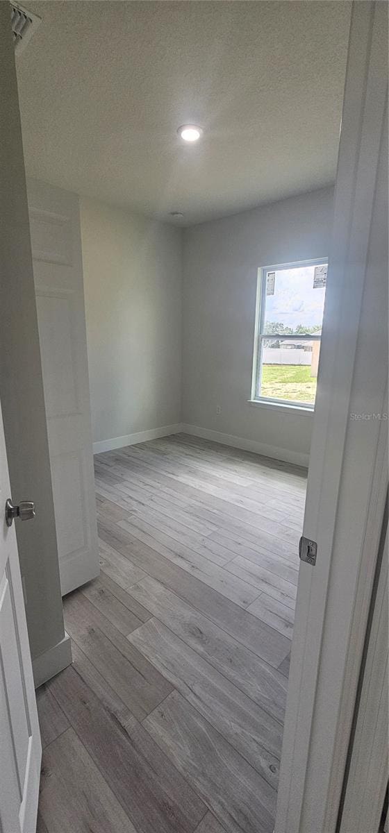 spare room with a textured ceiling and light hardwood / wood-style floors