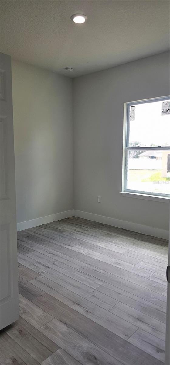 spare room featuring light wood-type flooring and a textured ceiling