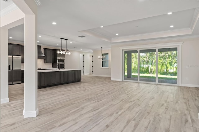 interior space with a chandelier, sink, light hardwood / wood-style flooring, a raised ceiling, and ornamental molding