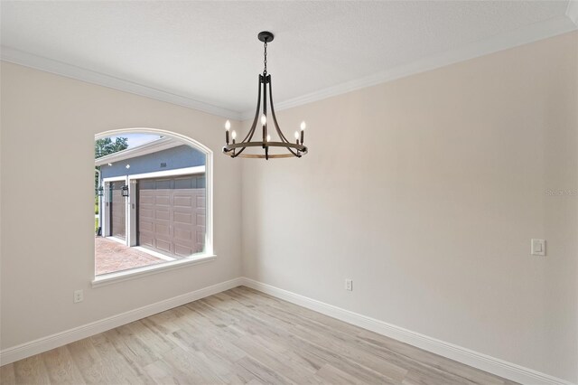 unfurnished room with light hardwood / wood-style flooring, plenty of natural light, an inviting chandelier, and crown molding