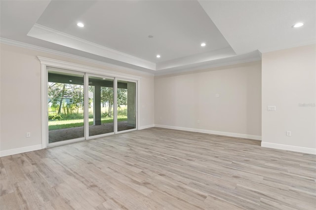 empty room featuring light wood-type flooring, crown molding, and a tray ceiling