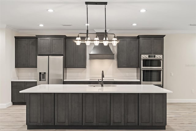 kitchen with an island with sink, light hardwood / wood-style floors, custom exhaust hood, and stainless steel appliances