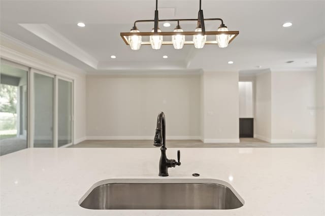 kitchen with ornamental molding, light stone counters, hanging light fixtures, and sink