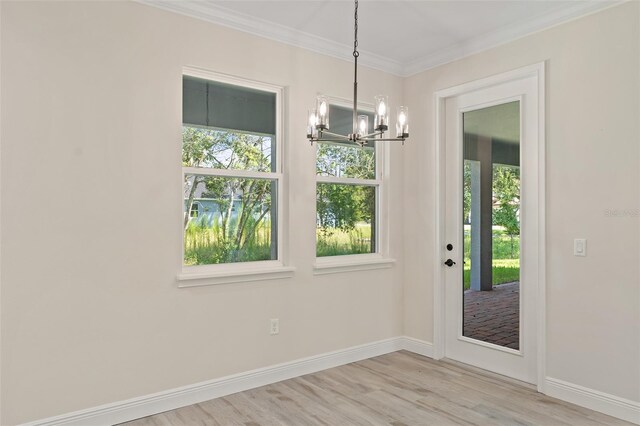 unfurnished dining area with light wood-type flooring, crown molding, and a notable chandelier