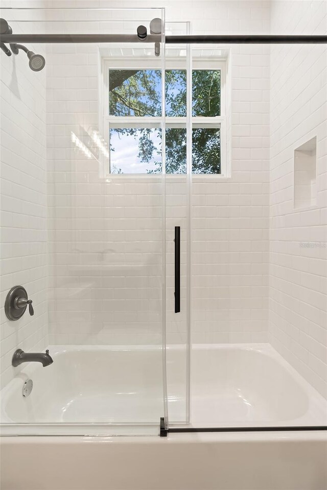 bathroom featuring bath / shower combo with glass door and a wealth of natural light