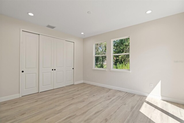 unfurnished bedroom featuring light hardwood / wood-style flooring and a closet