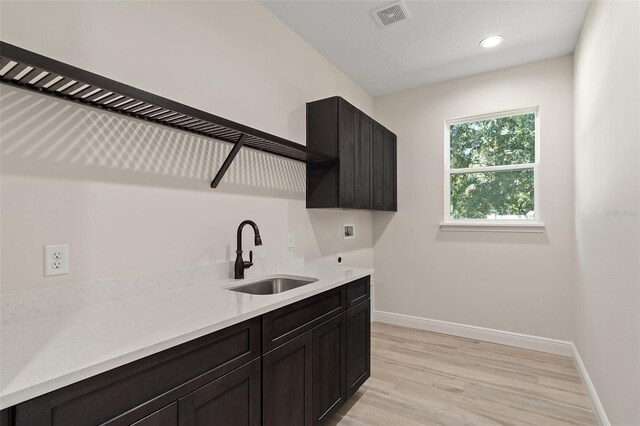 kitchen with light hardwood / wood-style flooring, dark brown cabinetry, and sink