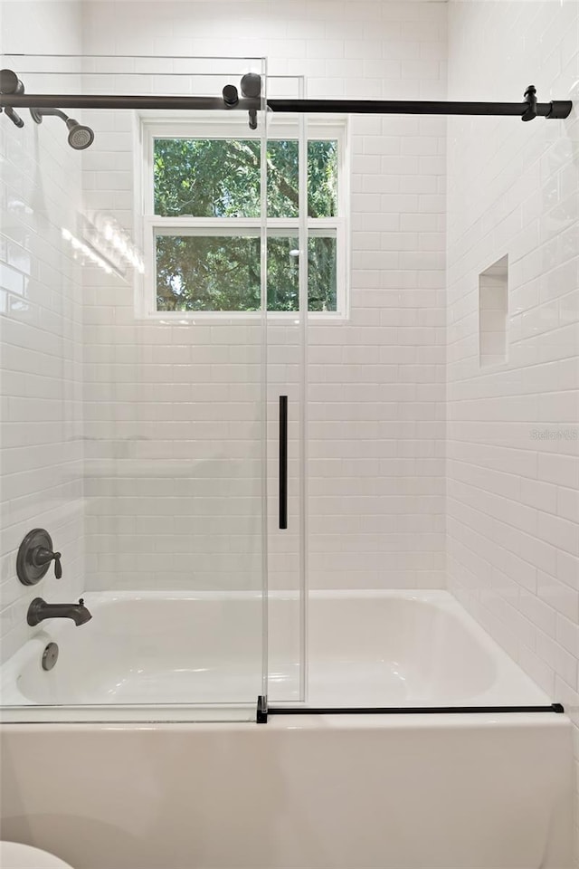 bathroom featuring bath / shower combo with glass door