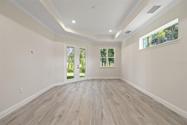 spare room featuring light hardwood / wood-style flooring, a tray ceiling, french doors, and crown molding