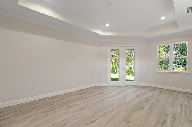 unfurnished room featuring light hardwood / wood-style flooring, a raised ceiling, plenty of natural light, and ornamental molding