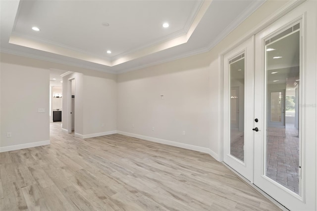 spare room with light wood-type flooring, a tray ceiling, french doors, and crown molding