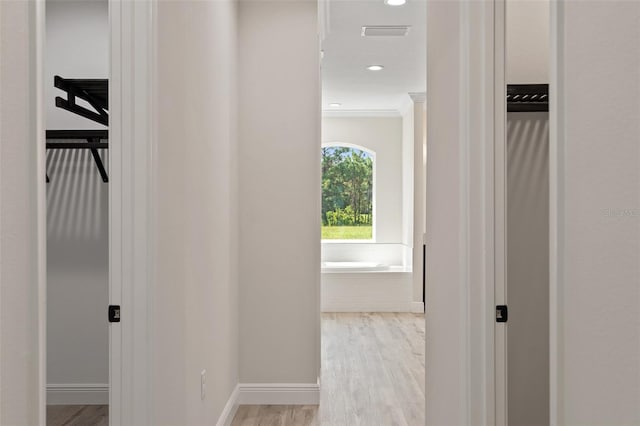 corridor featuring ornamental molding and light wood-type flooring