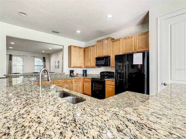 kitchen featuring black appliances, light stone counters, sink, and kitchen peninsula