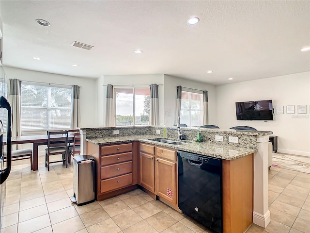 kitchen featuring light tile patterned floors, light stone counters, black dishwasher, and sink