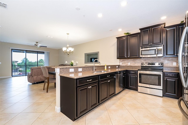 kitchen featuring pendant lighting, ceiling fan with notable chandelier, kitchen peninsula, sink, and appliances with stainless steel finishes