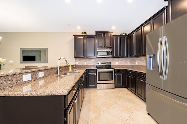 kitchen with light stone countertops, tasteful backsplash, stainless steel appliances, sink, and dark brown cabinetry