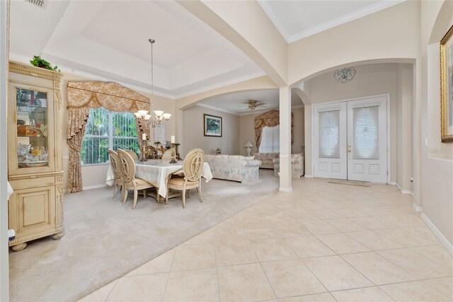 carpeted dining room with crown molding, a tray ceiling, ceiling fan with notable chandelier, and french doors