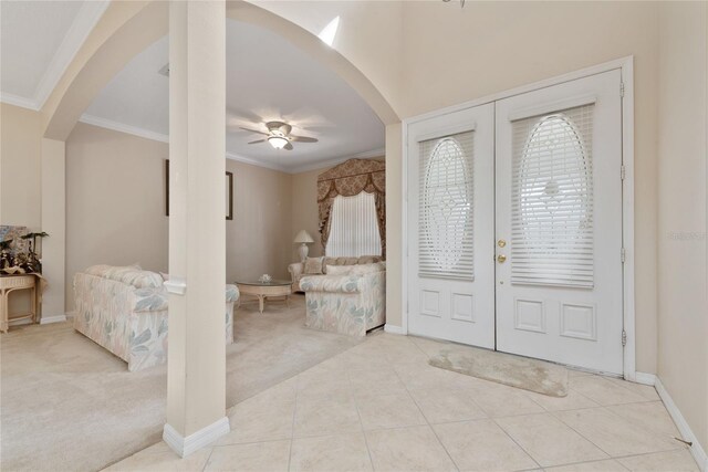 foyer entrance with crown molding, french doors, light colored carpet, and ceiling fan