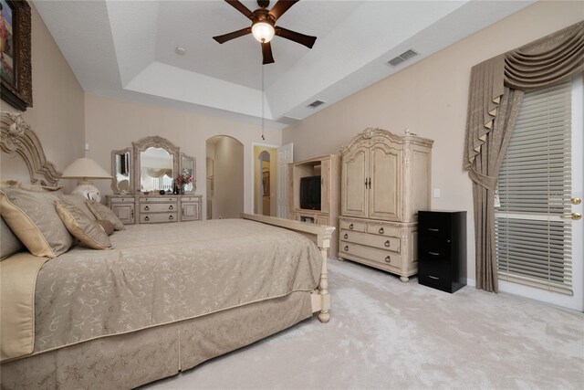 bedroom with light colored carpet, ceiling fan, and a tray ceiling