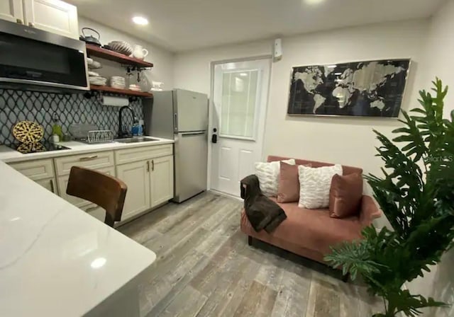 kitchen featuring light hardwood / wood-style flooring, stainless steel appliances, backsplash, and sink