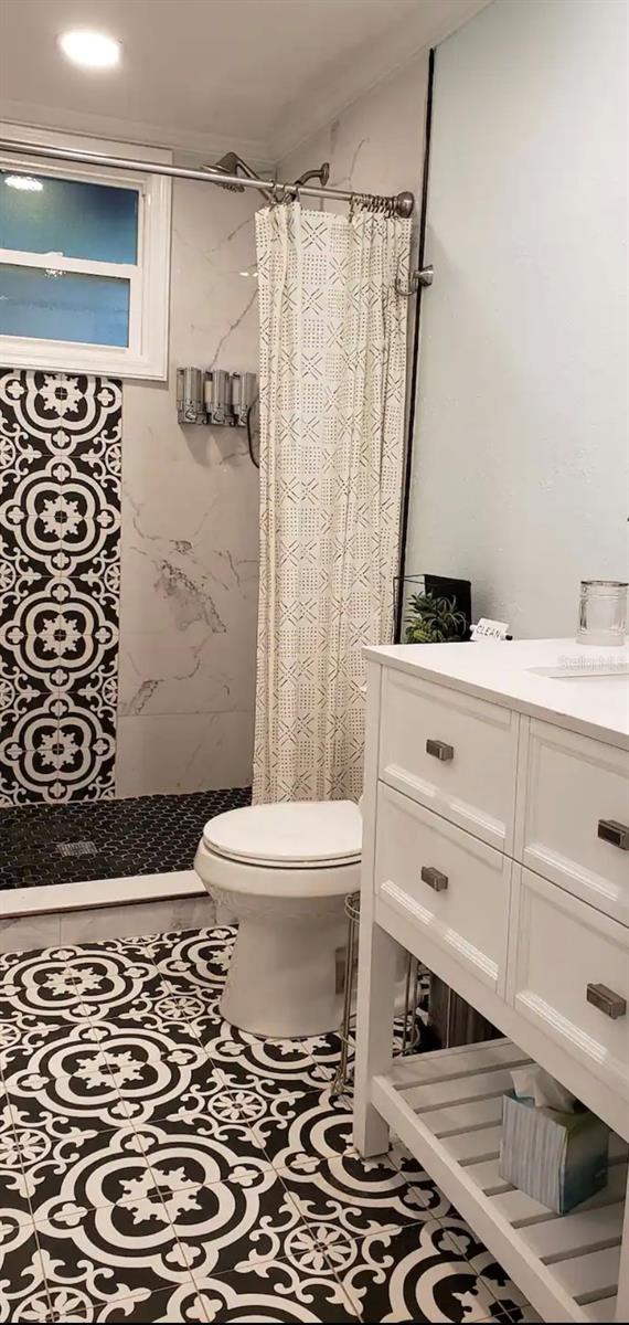 bathroom with a shower with curtain, vanity, tile patterned flooring, and toilet