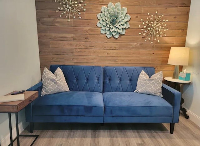 living room featuring hardwood / wood-style flooring, wooden walls, and a notable chandelier