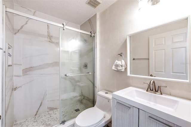 bathroom with a shower with door, vanity, a textured ceiling, and toilet