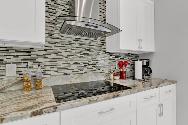 kitchen with range hood, white cabinetry, decorative backsplash, black electric cooktop, and light stone countertops