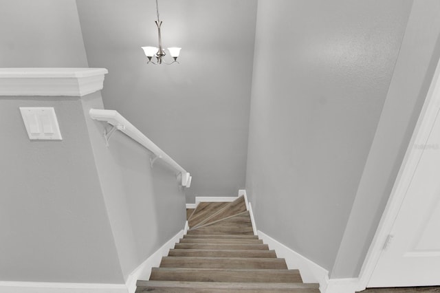 staircase featuring an inviting chandelier and wood-type flooring