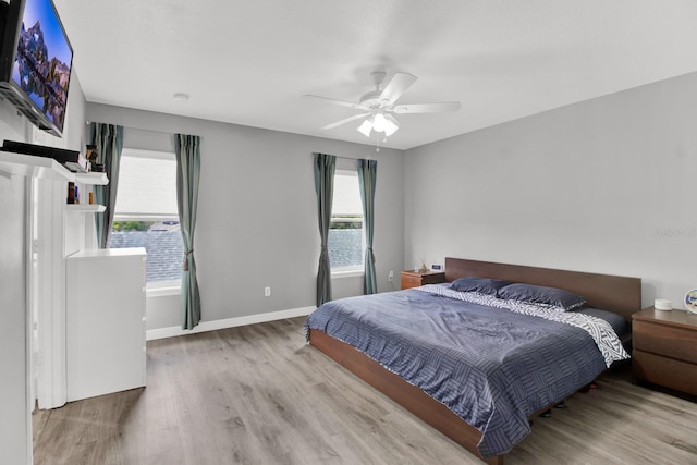 bedroom featuring ceiling fan, hardwood / wood-style floors, and multiple windows