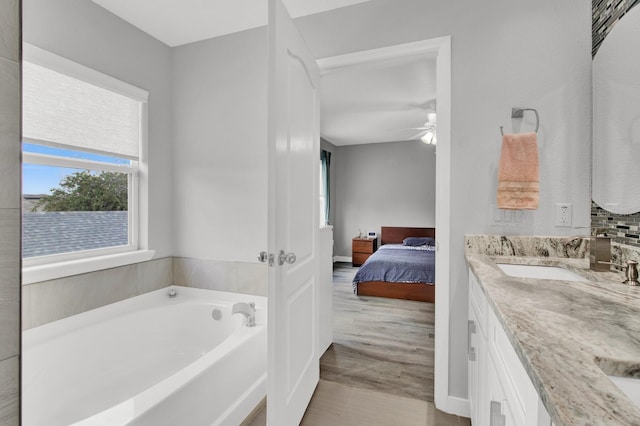 bathroom with wood-type flooring, ceiling fan, a tub, and vanity