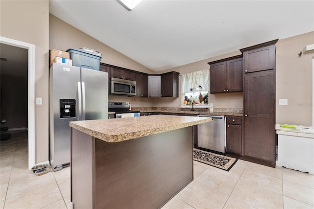 kitchen featuring light tile patterned floors, vaulted ceiling, a center island, appliances with stainless steel finishes, and dark brown cabinetry