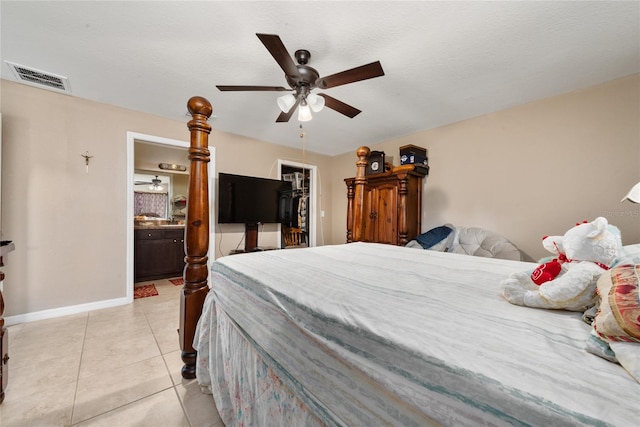 tiled bedroom with a textured ceiling, ensuite bath, ceiling fan, a closet, and a spacious closet