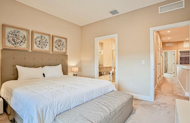 bedroom with light colored carpet and ensuite bathroom