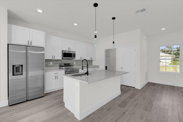 kitchen with a kitchen island with sink, appliances with stainless steel finishes, light hardwood / wood-style flooring, and sink