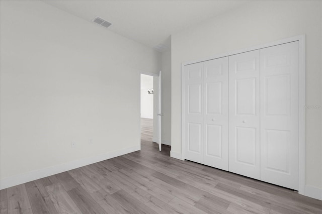 unfurnished bedroom with a closet, visible vents, baseboards, and wood finished floors