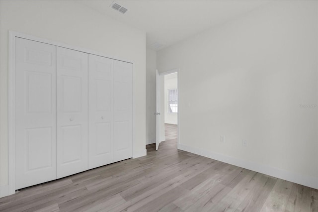 unfurnished bedroom featuring a closet, wood finished floors, visible vents, and baseboards