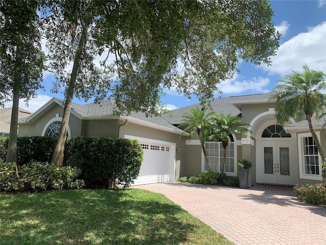 14421 Hatchee Ct, Orlando, FL 32837 - view of front of property featuring french doors, a garage, decorative driveway, a shingled roof, and stucco siding