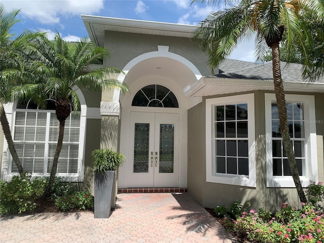 14421 Hatchee Ct, Orlando, FL 32837 - view of exterior entry featuring french doors, stucco siding, and roof with shingles