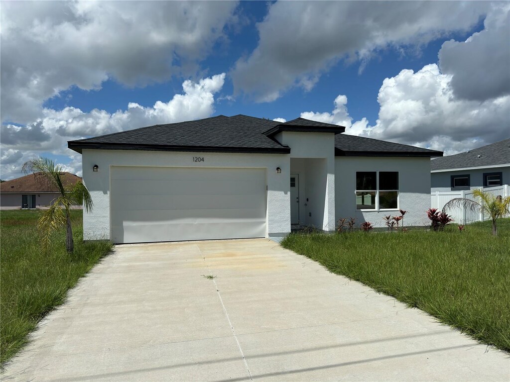 1204 Vero Beach Way, Poinciana, FL 34759 - view of front facade with stucco siding, fence, roof with shingles, concrete driveway, and an attached garage