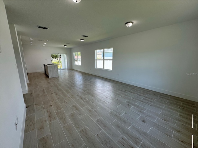 unfurnished living room with a textured ceiling and light hardwood / wood-style floors