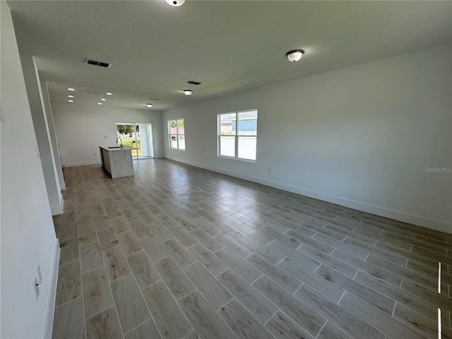empty room with baseboards, visible vents, and light wood finished floors