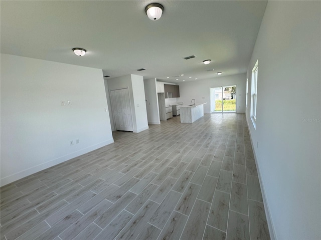 unfurnished living room featuring light wood-type flooring and sink