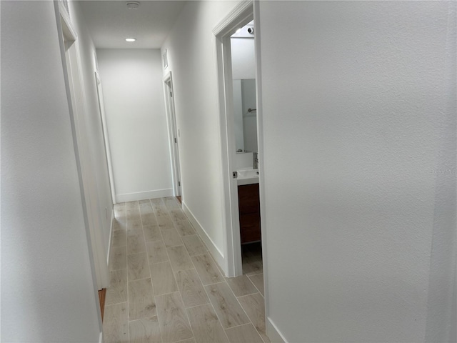 corridor featuring baseboards and wood finish floors