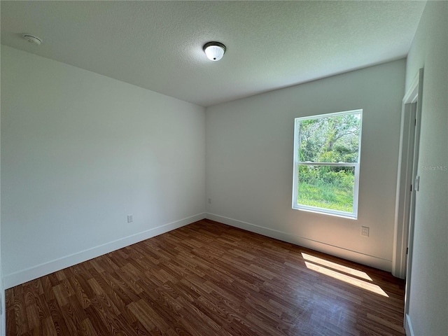 empty room with baseboards, dark wood-style flooring, and a textured ceiling