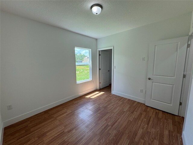 unfurnished bedroom featuring dark hardwood / wood-style flooring and a textured ceiling