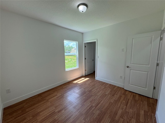unfurnished bedroom featuring baseboards, a textured ceiling, and wood finished floors